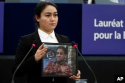 Джухия Ильхам держит портрет своего отца на церемонии вручения премии им. Сахарова. Страсбург, 2019 год.