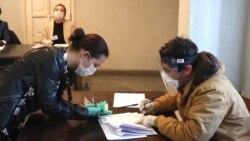 Nagorno-Karabakh -- A voter (L) and an election commission official at a polling station in Stepanakert, March 31, 2020.