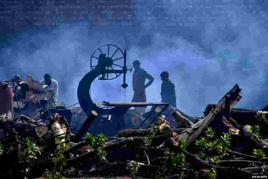 Pakistani laborers cut logs at a timber market in Lahore. (AFP/Arif Ali)