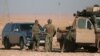 U.S. servicemen stand near military vehicles, north of Raqqa, in Syria earlier this month