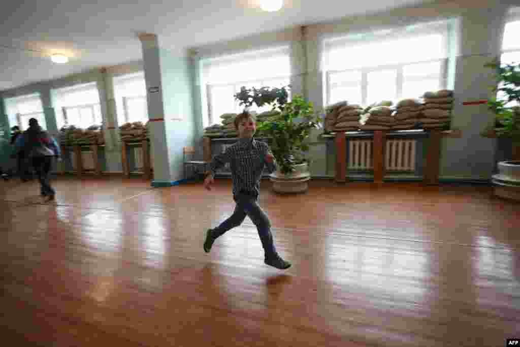 A boy runs past sandbags covering the windows of a school intended to protect children in case of shelling in the small Ukrainian town of Maryinka. (AFP/Aleksey Filippov)