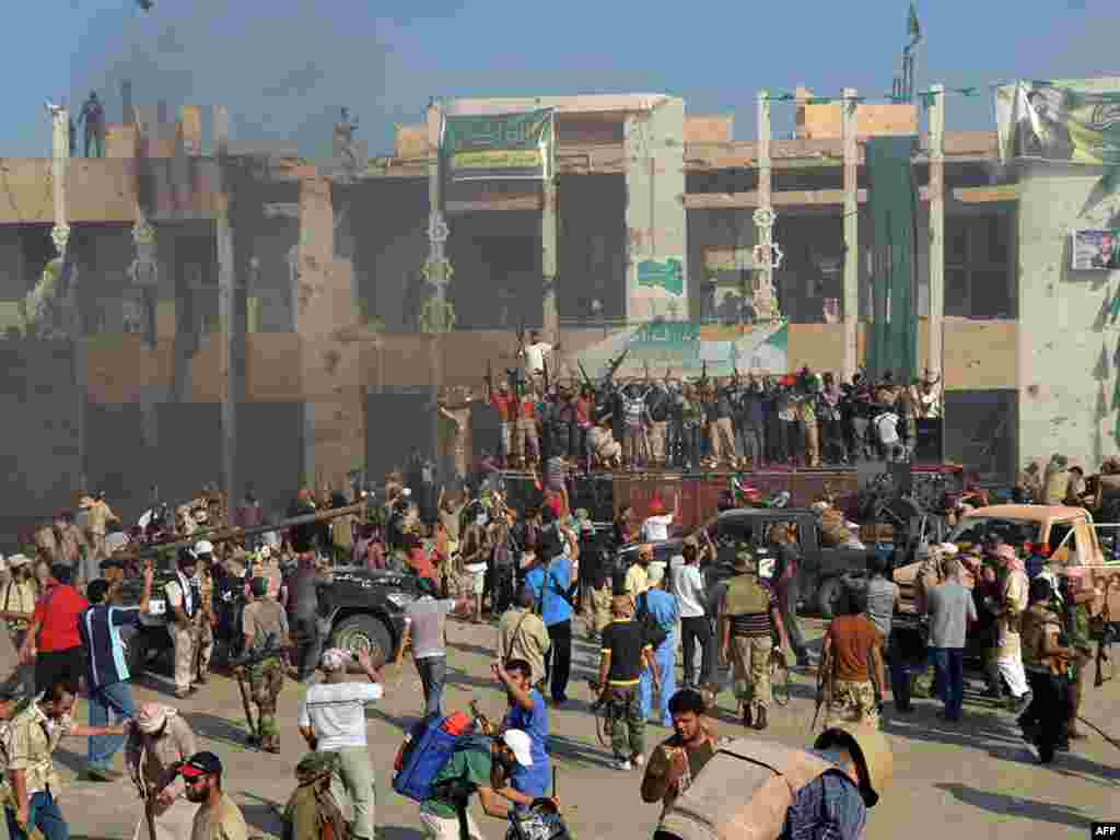 Rebels and their supporters celebrate outside Qaddafi's heavily damaged Bab al-Aziziya compound. 