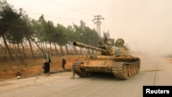 A tank with rebel fighters drives through an area of the embattled city of Aleppo, Syria, on October 28.
