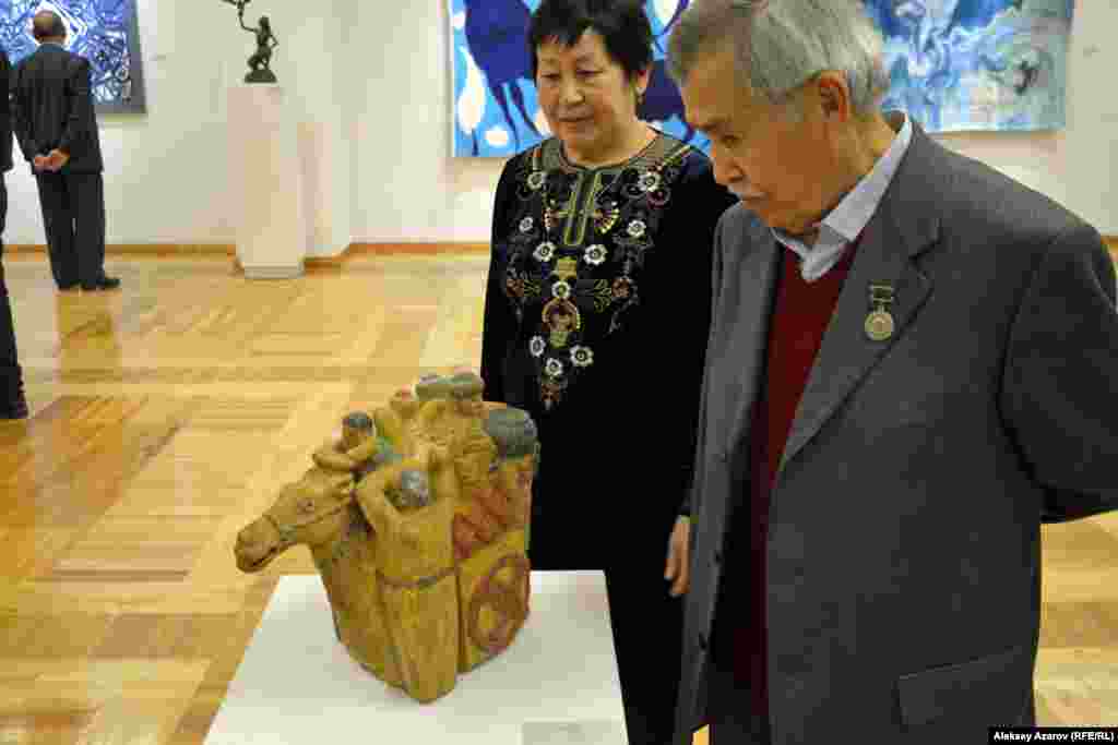Среди участников выставки – один из старейших художников Казахстана 80-летний Турсын Абуов. Он стоит рядом со своей скульптурной работой «Кочевники» (дерево). 