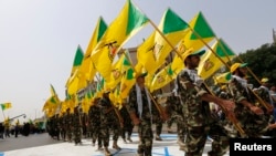 Men from the Iranian-backed group Kataib Hizballah wave party flags as they walk along a street painted in the colours of the Israeli flag during a parade marking the annual Quds Day, or Jerusalem Day, in Baghdad in 2014.