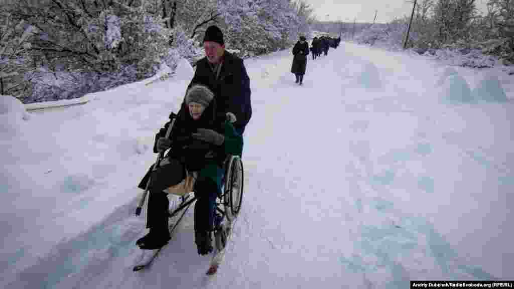 An elderly woman being pushed on her winter-modified wheelchair.&nbsp;