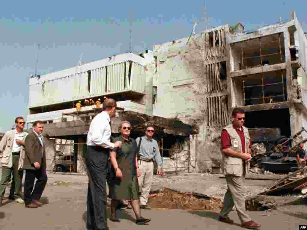 ABŞ-nyň Döwlet sekretary Medlin Olbraýt (ortada) Tanzaniýanyň paýtagty Dar es Salaamdaky ABŞ-nyň ilçihanasynyň binasynyň ýanynda, 1998-nji ýylyň awgust aýy. Bu ilçihana “Al-Kaýda” bomba hüjümini amala aşyrypdy. Wakada 11 adam heläk boldy.