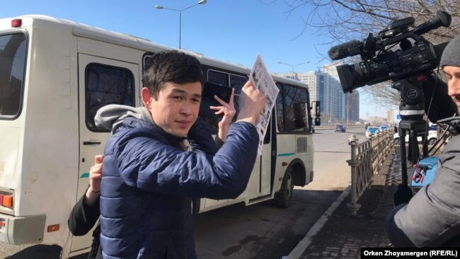 Молодой человек закрывает объектив видеокамеры листом бумаги, мешая оператору Азаттыка вести съемку. Астана, 22 марта 2019 года.