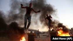 Палестинские студенты перепрыгивают через горящие шины, демонстрируя свои военные навыки, на юге сектора Газа, 23 сентября 2018 года