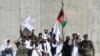 FILE: Afghan civilians carrying Afghan national flag along with Taliban flag stand with Taliban fighters and army soldiers to celebrate a three-day ceasefire on second day of Eid al-Fitr, in the outskirt of Kabul (June 2018).