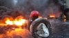 A protester carries tires to add to a burning pile at the site of clashes with riot police.