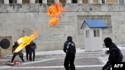 Greek riot police duck as a Molotov cocktail thrown by youths explodes in front of the parliament building in Athens on December 6, with a vote pending on the austerity budget.