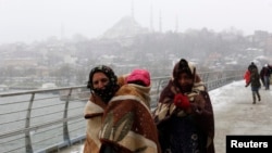 FILE: Syrian refugees brave the cold and snow as they walk to a metro station in Istanbul.