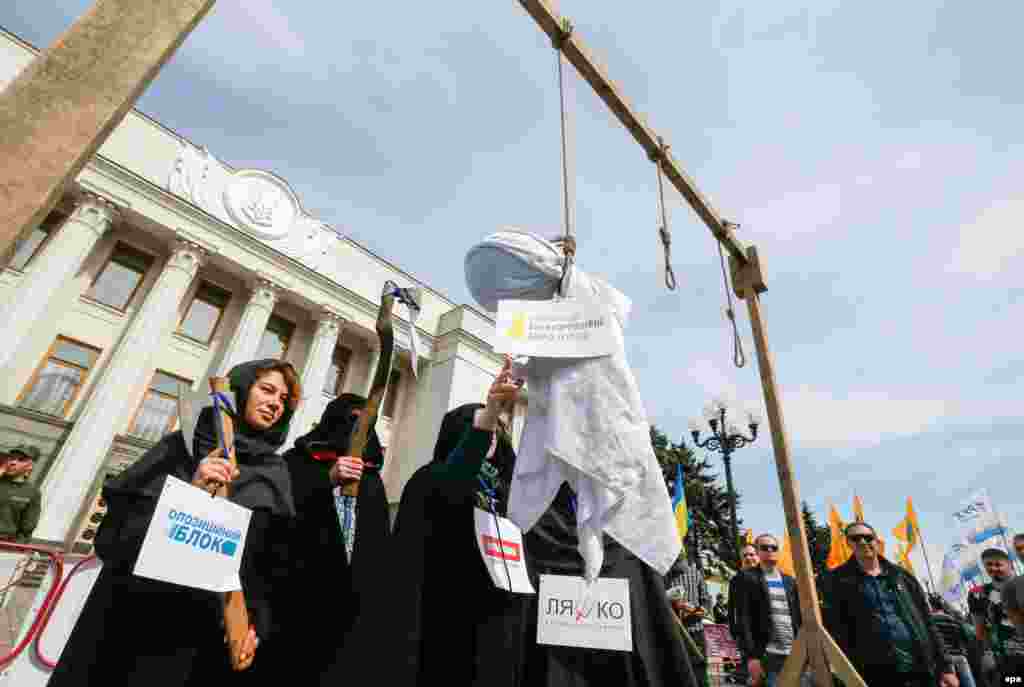 Activists wearing symbolic executioner's clothes hang an effigy with a sign reading "National Anticorruption Bureau of Ukraine" during a protest at parliament in Kyiv on May 16. (epa/Serhiy Dolzhenko)