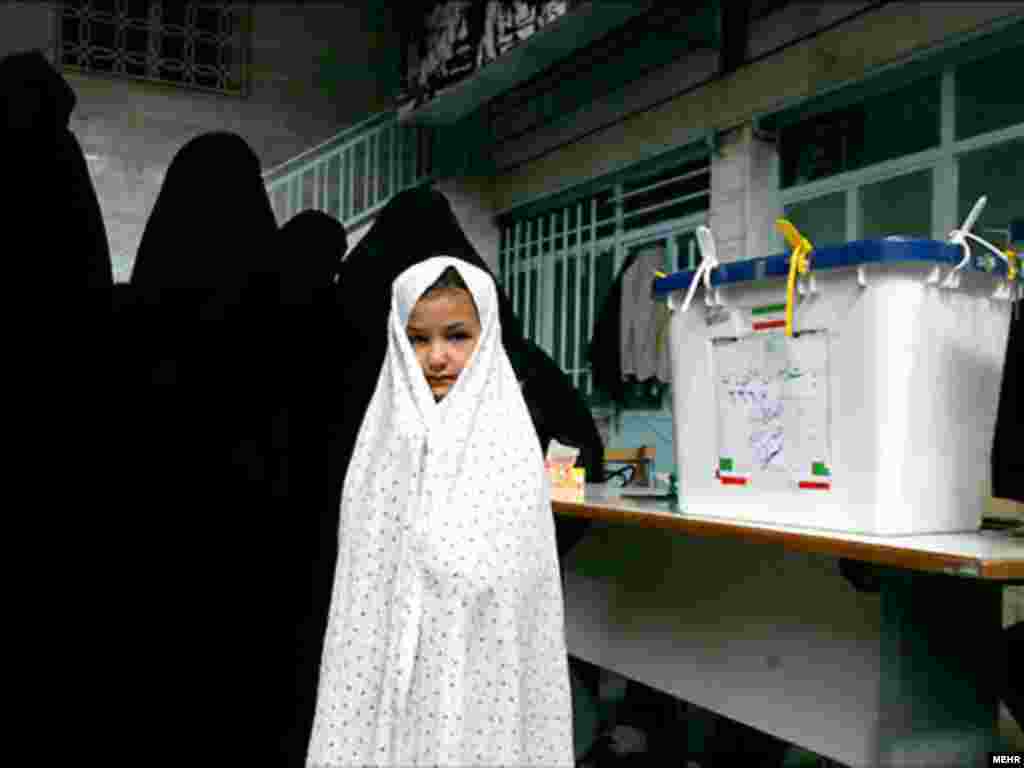 A girl waits while women vote at a Tehran polling station.