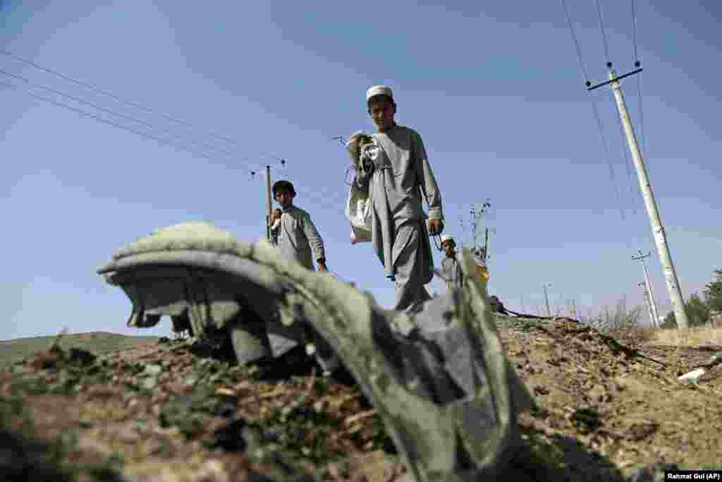 Afghan boys collect the remains of a suicide attacker's vehicle in Kabul. One Croatian soldier was killed and two seriously wounded in the attack on their convoy on July 24. (AP/Rahmat Gul)