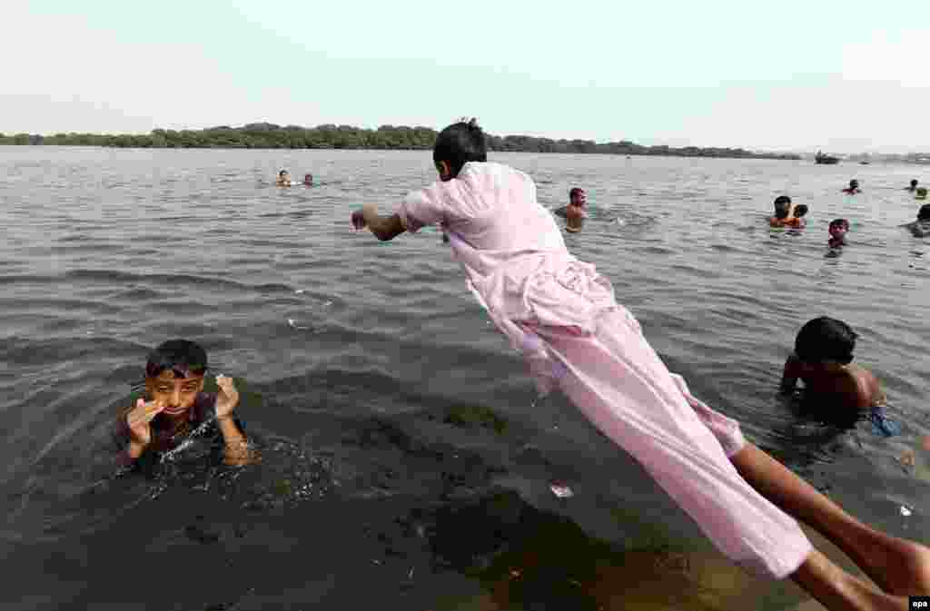 People jump into water to cool off in Karachi.