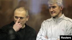 Jailed Russian former oil tycoon Mikhail Khodorkovsky (left) and his business partner Platon Lebedev stand in the defendants' cage before the start of a court session in Moscow in 2010.