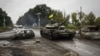 Украинский танк проезжает мимо бывшего российского контрольно-пропускного пункта в городе Изюм Харьковской области, ранее освобожденного Вооруженными силами Украины от российской армии, 16 сентября 2022 года