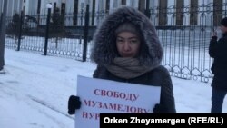 Жительница Астаны Асель Кали, участница одиночного пикета в поддержку своего брата — акима Талапкерского сельского округа Нуртугана Музамелова, подозреваемого по уголовным статьям, — с плакатом у генеральной прокуратуры Казахстана. Астана, 9 января 2018 года. 