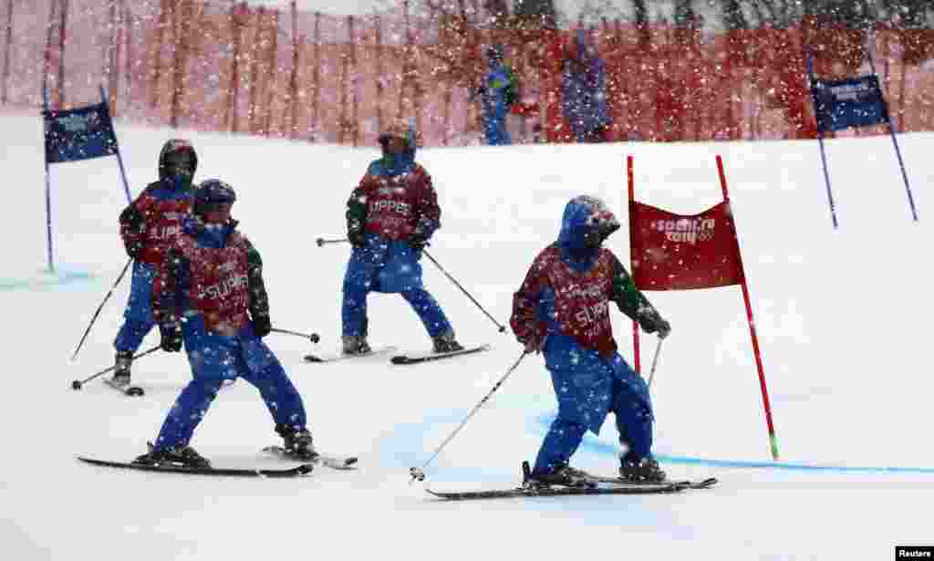 Course slippers clear fresh snow from the track before the second run of the women's alpine-skiing giant slalom event. (Reuters/Dominic Ebenbichler)
