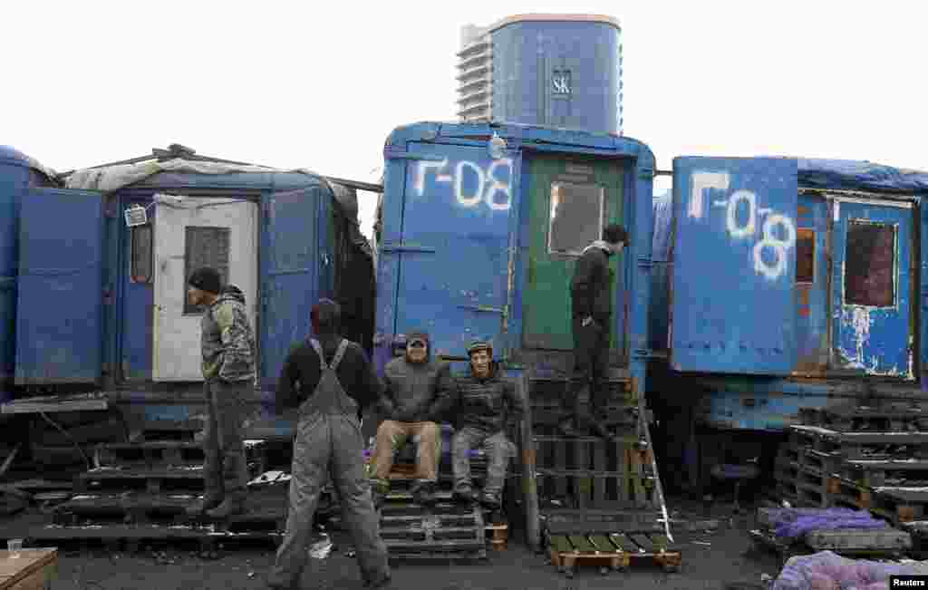 Мужчины в ожидании начало работы на овощном рынке в пригороде Москвы. 2011.