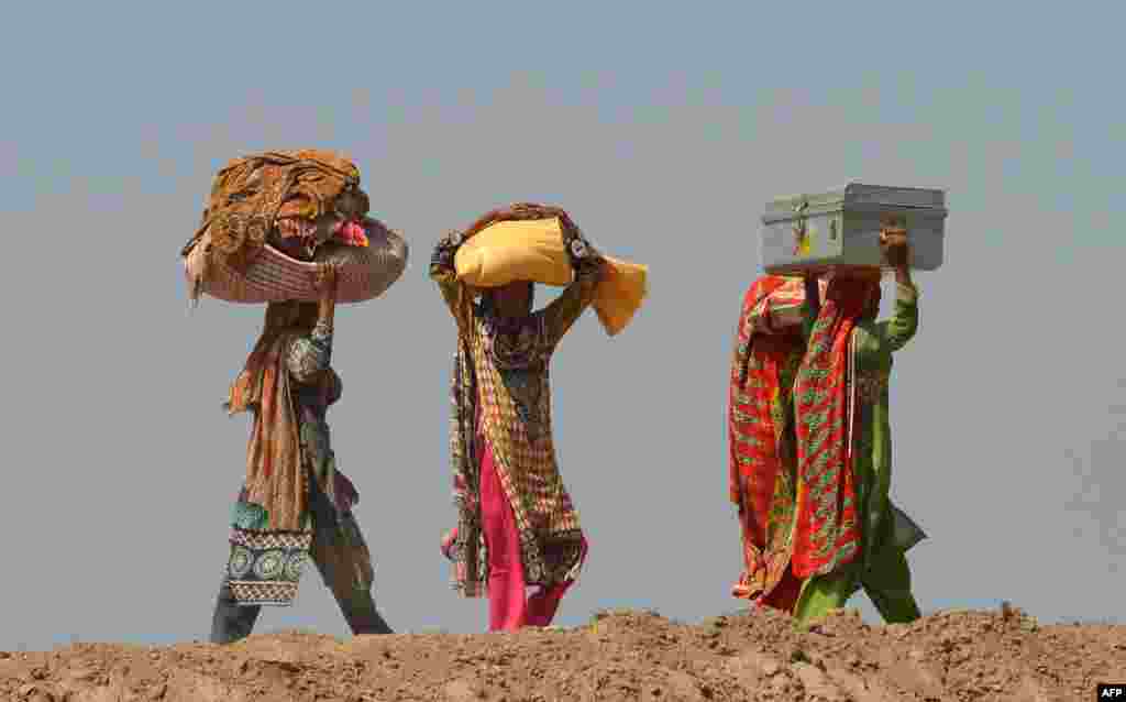 Pakistani residents affected by flooding carry their belongings as they make their way to higher ground at a village in Jhang in central Punjab Province.