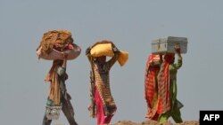Pakistanis affected by floods carry their belongings as they make their way to higher ground at a village in Jhang, in the central Punjab province, September 9, 2014.