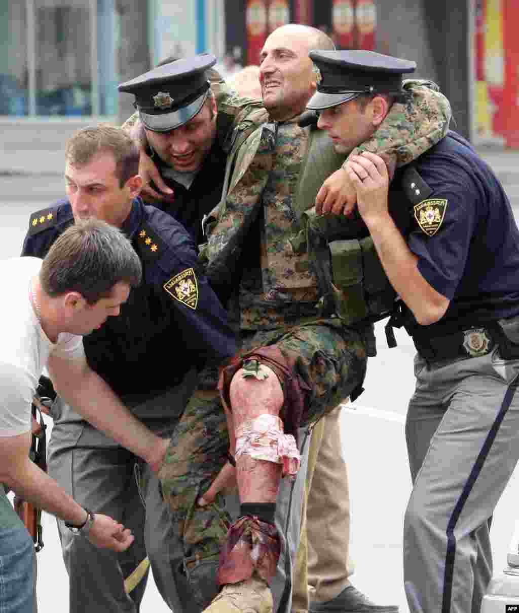Полицейские оказывают помощь грузинскому солдату, раненому в бою с южноосетинскими сепаратистами в Гори. 8 августа 2008 года. &nbsp;