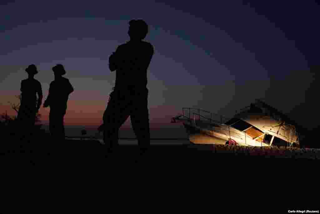 Workmen load heavy equipment onto a trailer in front of a destroyed boat that came ashore following Hurricane Irma in Summerland Key, Florida. (Reuters/Carlo Allegri)