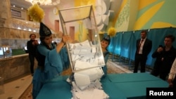 Члены избирательной комиссии опрокидывают урну с бюллетенями после закрытия избирательного участка в Алматы в день президентских выборов. 9 июня 2019 года.