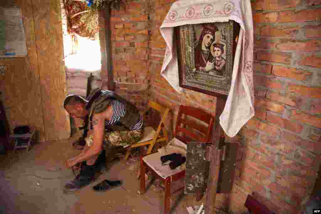 A Ukrainian serviceman laces up his boots in an Orthodox church destroyed after helling between Ukrainian forces and pro-Russian separatists in the village of Pisky in the Donetsk region. (AFP/Oleksandr Ratushniak)