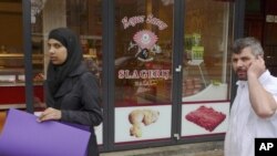 Mesar razgovara telefonom ispred halal mesare u Amsterdamu