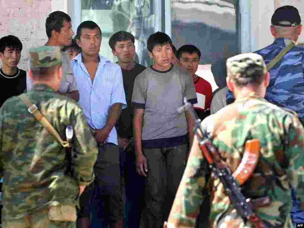 Security forces search detained ethnic Uzbeks after a military operation in the village of Nariman.