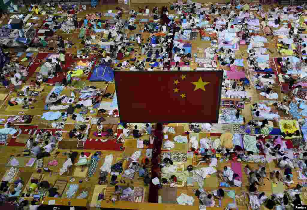 Students prepare to sleep on mats laid out on the floor under a Chinese national flag inside a gymnasium at the Huazhong Normal University in Wuhan, Hubei Province, China. More than 1,000 students slept inside the gymnasium to escape the hot weather in Wuhan, which reached 35 degrees Celsius on June 29. (Reuters/Stringer)