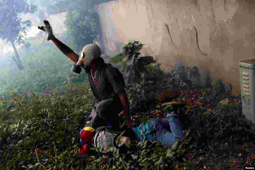 Një protestues i lënduar ndihmohet nga një protestues tjetër. Protestuesit u përleshën me policinë në protestat në Venezuelë, që u organizuan kundër presidentit, Nicolas Maduro.