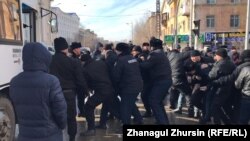Полиция көшеден ұстаған адамдарды көлікке күштеп салып жатыр. Ақтөбе, 22 ақпан 2020 жыл.