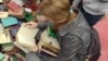 KitapFest-2015 шарасында кітап қарап отырған қыз. Алматы, 5 қыркүйек 2015 жыл. 