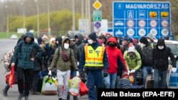 Poliția maghiară escortează un grup de muncitori migranți la punctul de trecere Zahony, de la granița cu Ucraina, martie 2020