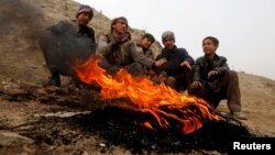 Afghan youth warm themselves by a fire during a cold day on the outskirts of Kabul last week.