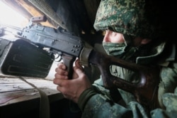 A separatist militant peers out a dugout on the front line with Ukrainian troops in the Donetsk region.
