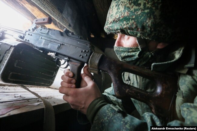 A separatist militant peers out a dugout on the front line with Ukrainian troops in the Donetsk region.
