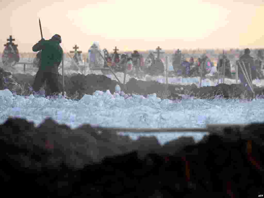 Workers dig graves for victims of a nightclub fire in Perm, Russia. - A fire that raged through a nightclub in the Russian city of Perm on December 4 killed 135 people and injured many others. Photo by AFP