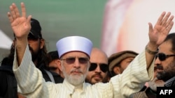 Muhammad Tahir-ul-Qadri waves to supporters on his arrival in Lahore on December 23.