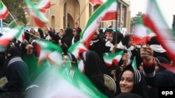 Iranian students wave national flags at the Behesht-e Zahra cemetery in Tehran on February 1.