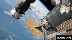 The Russian Soyuz MS-09 crew craft (left) attached to the International Space Station in June