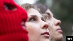 Nadezhda Tolokonnikova (right) and Maria Alyokhina (center), and a masked Pussy Riot activist are pictured during a news conference held outside a hotel in a park in Sochi on February 20.