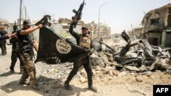 Members of the Iraqi Counterterrorism Service cheer as they carry an upside-down flag of the Islamic State extremist group, with the destroyed Grand Al-Nuri Mosque seen in the background, in the Old City of Mosul on July 2.