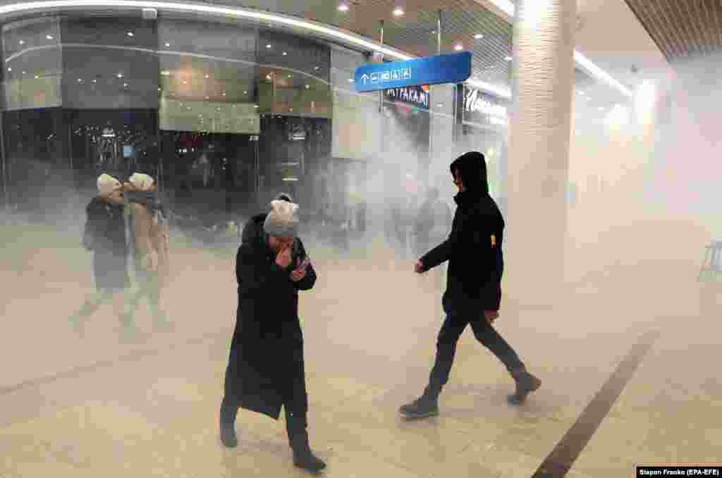 Visitors leave a shopping mall after it was attacked with smoke grenades during a protest by Ukrainian nationalists in Kyiv. Activists were protesting the presence of Russian-owned businesses in Ukraine. (EPA-EFE/Stepan Franko)