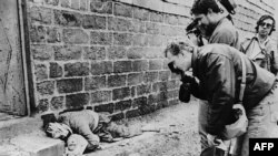 Photograph and cameraman take pictures on March 20, 1988 of a Kurdish father holding his baby in his arms in Halabja, northeastern Iraq. Both were killed in an Iraqi chemical attack on the city. AFP PHOTO/STR / AFP PHOTO / IRNA